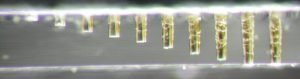 The varying depths of the holes are due to different increments in the number of laser pulses, ranging from 500 pulses to 4500 pulses, at which point the laser breaks through the glass.